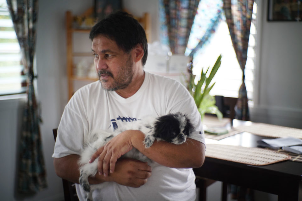 Jay Dela Pina holds his daughter’s dog at his home in Hilo. His workers’ comp carrier denied treatment based on a report by a doctor it hired even after a hearing officer said the doctor’s findings were not enough to block the claim.